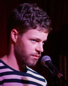 Caucasian man with beard at mic with striped tshirt